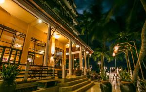 a building with palm trees in front of it at Rayong Resort Hotel in Ban Phe