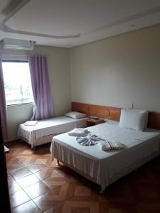 a hotel room with two beds and a window at Hotel Litoral in Aracaju