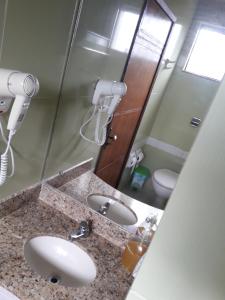 a bathroom with a sink and a mirror and a toilet at Hotel Litoral in Aracaju