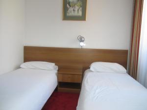 dos camas sentadas una al lado de la otra en una habitación en Hotel Grand en Sarajevo