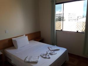 a bedroom with a white bed with a large window at Hotel Litoral in Aracaju