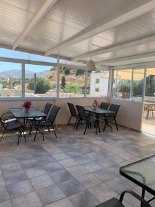 a patio with tables and chairs and windows at Pension Nikos in Pitsidia