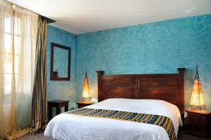 - une chambre avec un lit et un mur bleu dans l'établissement Hôtel & Spa du Domaine des Thômeaux, The Originals Relais (Relais du Silence), à Mosnes