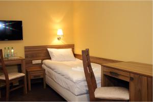 ein Hotelzimmer mit einem Bett, einem Schreibtisch und einem Fernseher in der Unterkunft Hotel Ambasada in Krobia
