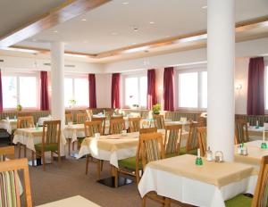 um restaurante com mesas e cadeiras e cortinas vermelhas em Hotel Hierzegger em Tauplitzalm