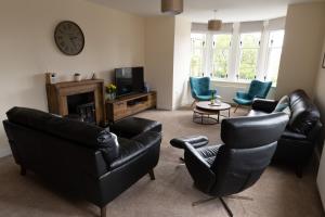a living room with black leather furniture and a clock at Harbour Street Apartment in Lerwick