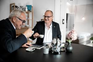 two men in suits sitting at a table with a laptop at Logierhaus M in Esens