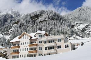un hotel nella neve con una montagna sullo sfondo di Alpenstern - Sommer Silvretta Card Premium inklusive! a Ischgl