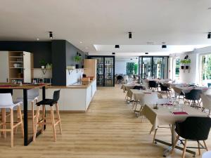 een restaurant met tafels en stoelen en een keuken bij ibis Styles Lille Neuville en Ferrain in Neuville-en-Ferrain