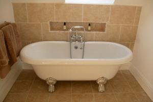 a white bath tub in a bathroom with a window at Thatched Cottage in Hungerford