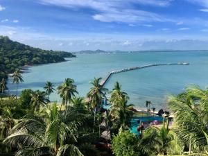 Blick auf das Meer mit Palmen und einem Pier in der Unterkunft Rayong Resort Hotel in Ban Phe
