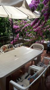 un tavolo bianco con sedie, ombrellone e fiori di Holiday House Camillina a Salò