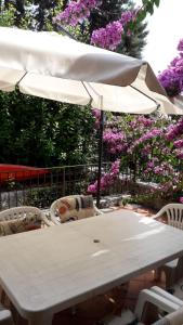 un tavolo bianco con sedie e ombrellone di Holiday House Camillina a Salò