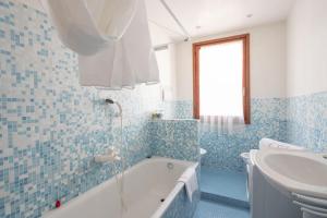 a blue tiled bathroom with a tub and a sink at Ca' Coriandolo in Venice