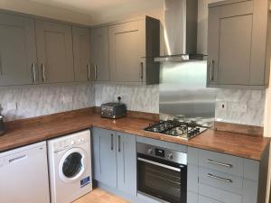 uma cozinha com armários brancos e um forno com placa de fogão em Seacroft em Kingsdown