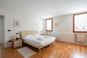 a bedroom with a bed and a table and two windows at Ca' Coriandolo in Venice