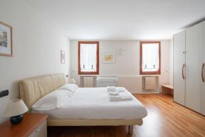 a white bedroom with a bed and two windows at Ca' Coriandolo in Venice