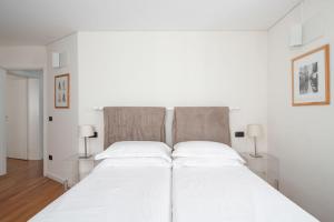 a white bed in a white bedroom with two lamps at Ca' Coriandolo in Venice