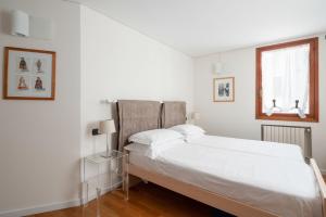 a white bedroom with a large bed and a window at Ca' Coriandolo in Venice