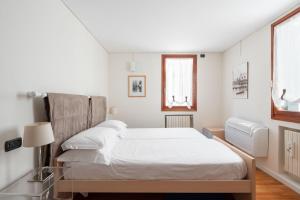 a white bedroom with a bed and two windows at Ca' Coriandolo in Venice