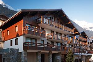 a large apartment building with balconies and snow covered mountains at Lagrange Vacances Les Chalets du Mont Blanc in Hauteluce