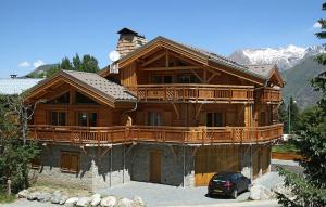una grande casa in legno con un'auto parcheggiata di fronte di Odalys Chalet Levanna Orientale a Les Deux Alpes