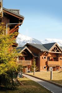 ein großes Holzgebäude mit Bergen im Hintergrund in der Unterkunft Lagrange Vacances Les Fermes de Samoëns in Samoëns