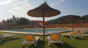 a group of chairs and an umbrella next to a pool at Domaine des voiles de Pierrefeu in Pierrefeu-du-Var