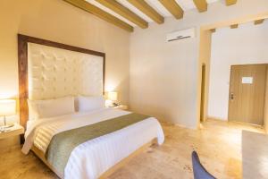 een slaapkamer met een groot bed en een stoel bij GHL Collection Armería Real Hotel in Cartagena