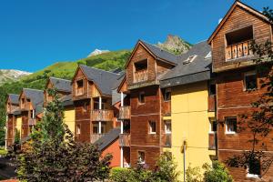 una fila de casas con montañas en el fondo en Lagrange Vacances Le Domaine des 100 Lacs, en Cauterets