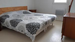 a bed with a black and white comforter on it at Villa patio à 200 m de la plage à Capbreton in Capbreton