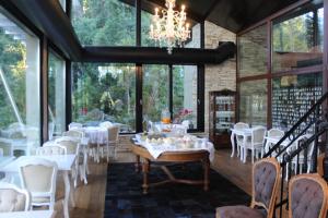 a dining room with white tables and chairs and a chandelier at Calfuco Wine Hotel & Spa in Villa La Angostura