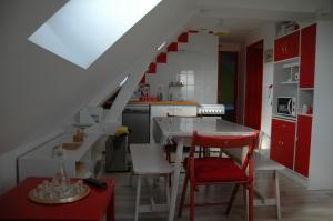eine Küche mit roten und weißen Schränken und einem roten Stuhl in der Unterkunft le four à pain in Faverolles