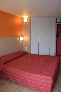 Una gran cama roja en una habitación con paredes de color naranja. en Premiere Classe Creil - Villers Saint Paul, en Villers-Saint-Paul