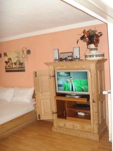 a television in a wooden cabinet in a bedroom at Haus Hönigsgrub in Rinchnach