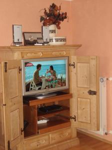 a television in a wooden entertainment center with two people at Haus Hönigsgrub in Rinchnach