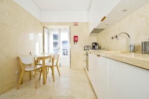 a kitchen with white cabinets and a table and chairs at Chiado Design Apartment 5E in Lisbon