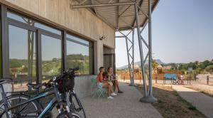 two people sitting on a chair outside of a building at Les Lodges de la ViaRhôna - Tentes Lodges in Virignin