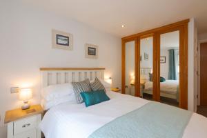 a bedroom with a large white bed with blue pillows at The Beach House & Porth Sands Apartments in Newquay