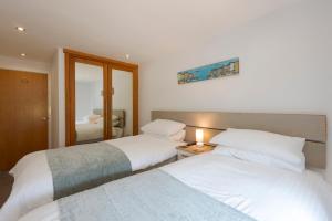 a bedroom with two beds and a mirror at The Beach House & Porth Sands Apartments in Newquay