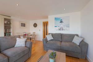 a living room with two couches and a table at The Beach House & Porth Sands Apartments in Newquay