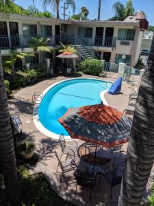 una piscina con sillas y sombrillas frente a un hotel en Tarzana Inn, en Tarzana