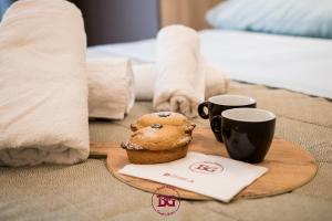 - un plateau avec un muffin et 2 tasses sur le lit dans l'établissement Dimora Elizabeth, à Modugno