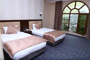 two beds in a hotel room with a window at Ruma Qala Hotel in Sheki
