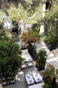 a garden with tables and potted plants on a patio at Les Jardins du Faubourg Hotel & Spa by Shiseido in Paris