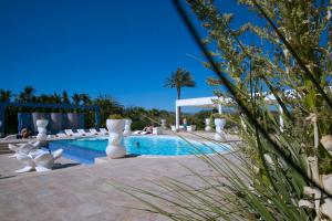 una piscina in un resort con sedie bianche intorno di Borgo degli Angeli a Balestrate