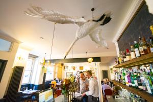 um grupo de pessoas num restaurante com pássaros pendurados no tecto em The Crooked Swan em Crewkerne