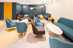 a waiting room with blue chairs and tables at Hôtel Acadia in Lourdes