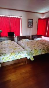 two beds in a bedroom with red curtains at Miyakojima - house / Vacation STAY 270 in Miyako Island