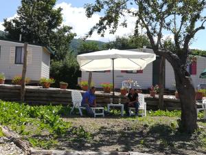 dos personas sentadas bajo un paraguas en un patio en Lago Secco Bed & Breakfast Country House en Accumoli